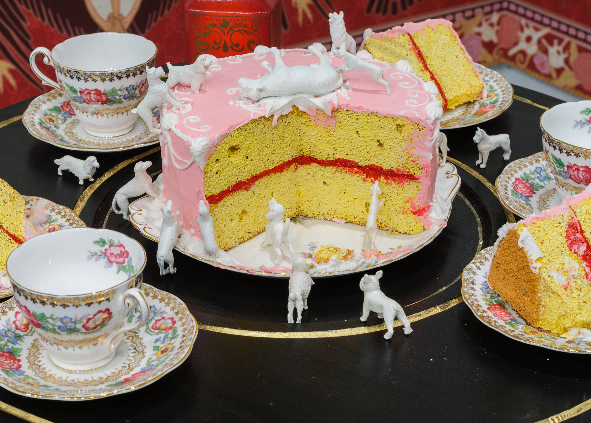 a close up of a pink cake with miniature white animals and tea cups and saucers around it